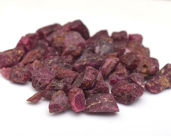Peut inclure: Un tas de pierres précieuses de rubis bruts, affichant une teinte rouge foncé avec des touches de brun et d'or. Les pierres précieuses sont de forme irrégulière et de tailles variées, sur fond blanc. Idéal pour la joaillerie ou la collection.