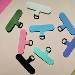 May include: Assortment of eight colorful, rectangular, fabric cable ties with a metal ring. The ties are in various colors, including green, pink, light blue, white, turquoise, and purple.