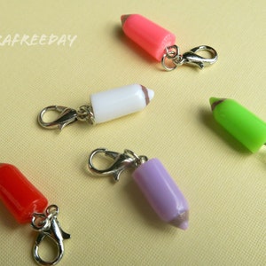 May include: Five colourful pencil-shaped charms with silver lobster clasps. The charms are pink, white, green, red and purple.