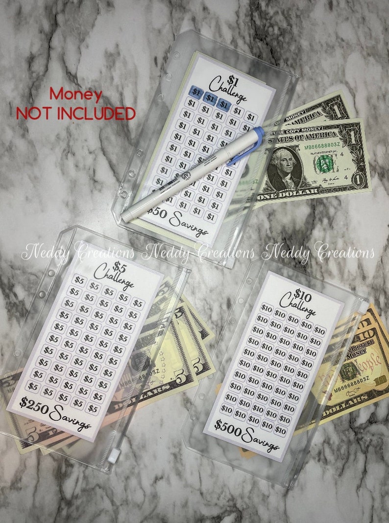 May include: Three clear plastic zippered pouches with printed sheets inside. Each sheet has a savings challenge with a dollar amount and a grid of squares to track progress. The pouches contain cash bills of $1, $5, and $10. The text on the sheets reads "$1 Challenge", "$5 Challenge", and "$10 Challenge". The sheets also have the text "$50 Savings", "$250 Savings", and "$500 Savings".