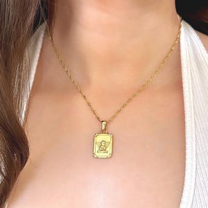 Dainty gold angel necklace worn on model showing 18k gold rectangular cherub pendant at collarbone length