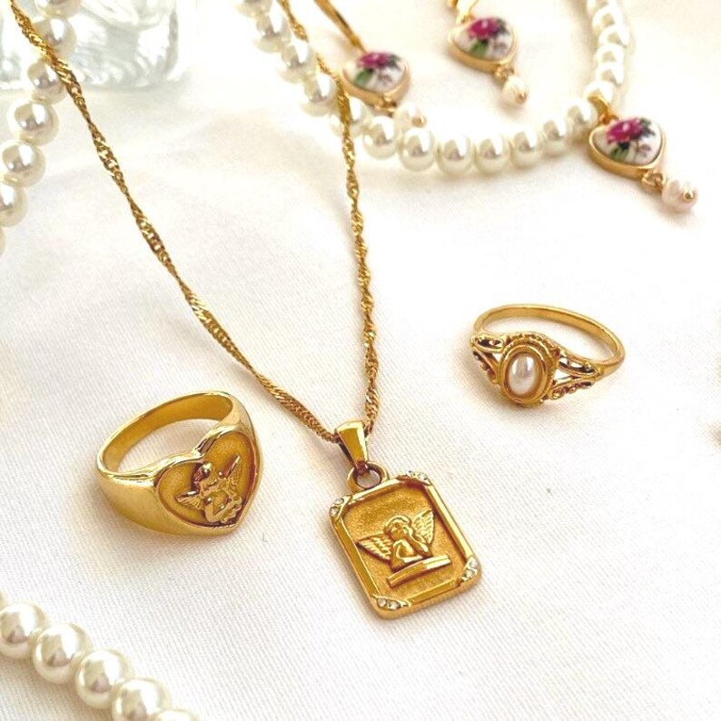 18k gold angel pendant necklace styled with pearl jewelry and gold rings for elegant coquette look