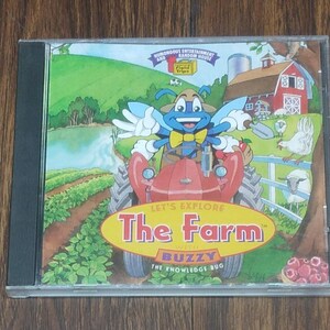 May include: A CD case featuring a colorful illustration of a farm scene. The cover art includes a red tractor, a cartoon bug character, a barn, and the text "LET'S EXPLORE The Farm with Buzzy The Knowledge Bug."