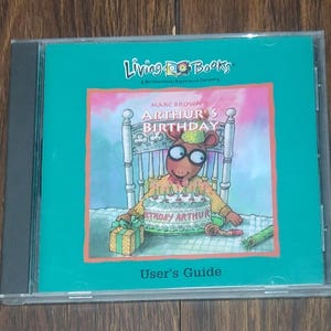 May include: A CD case featuring the book "Arthur's Birthday" by Marc Brown. The cover art shows Arthur the aardvark at a birthday party with a cake. The text "User's Guide" is at the bottom.