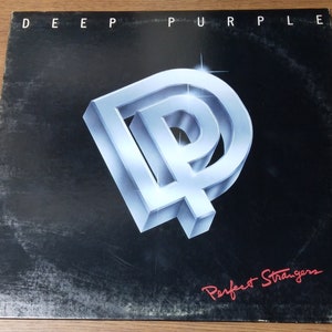 May include: A black vinyl record album cover with a silver 3D logo of the letters "DP" and the text "Deep Purple" at the top and "Perfect Strangers" in red cursive at the bottom.