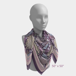 May include: A square scarf, 50 x 50 inches, featuring a floral design in shades of purple, pink, and yellow. The scarf is draped on a mannequin, showcasing its pattern and shape. The border has stripes of pink, blue, and purple.