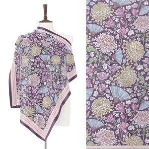 May include: A square scarf with a floral pattern featuring large chrysanthemums, fans, and other flowers in shades of purple, pink, and cream. The scarf has a dark purple border with pink and white stripes. The scarf is draped over a mannequin.