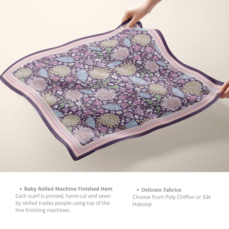 May include: A square scarf with a floral pattern in shades of purple, pink, and blue. The scarf features a border with a pink stripe and is held up by hands. The design includes flowers and fan shapes.