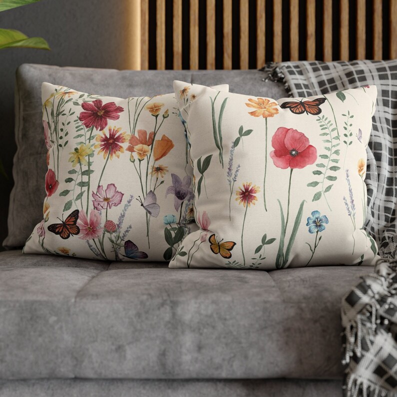 May include: Two decorative throw pillows with a floral pattern featuring butterflies, flowers, and leaves on a white background.
