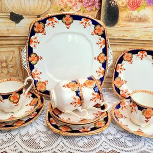 May include: A vintage tea set with a blue and gold floral pattern. The set includes a teapot, creamer, sugar bowl, and four teacups and saucers.