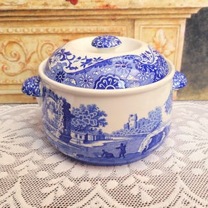 May include: A blue and white ceramic casserole dish with a lid. The dish features a traditional blue and white pattern with a landscape scene.