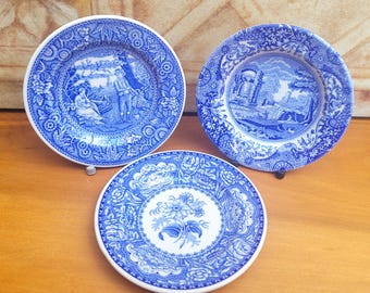 May include: Three blue and white decorative plates with detailed landscape and floral designs. The plates feature a classic blue transferware style, with intricate patterns around the edges and central images.