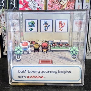 May include: A clear plastic cube with a miniature Pokemon scene inside. The scene features a Pokemon trainer standing in front of a bookshelf with three Pokemon on the wall. The text "Oak: Every journey begins with a choice." is printed on the bottom of the cube.