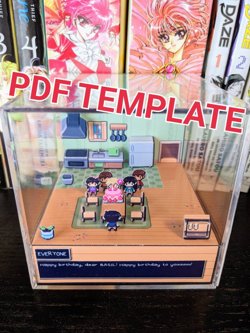 May include: A 3D papercraft diorama depicting a birthday party scene. The diorama is housed within a clear acrylic box. The scene features a table with a birthday cake, chairs, and pixelated characters. The text "EVERYONE" and "Happy birthday, dear BASIL! Happy birthday to youuuuu!" is visible at the bottom of the diorama.