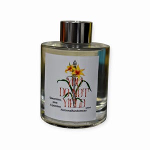 May include: A clear glass bottle with a silver cap. The label features a sword, yellow flowers, and the words "DO NOT YIELD". Below the text are the words "Spearmint, pine & jasmine" and "Fictionalfandomsau". The bottle contains 125ml.