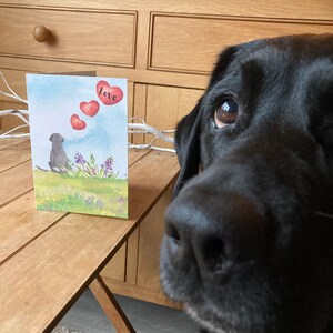 May include: A watercolor card with a black dog silhouette and red hearts floating above it. The card says "love" on the top right corner.