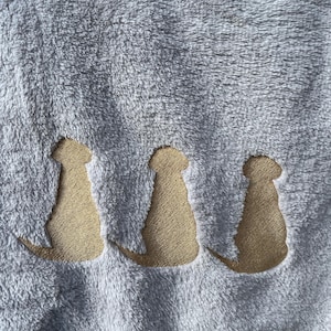 May include: A soft, gray fleece blanket with three embroidered dog silhouettes in a tan color.