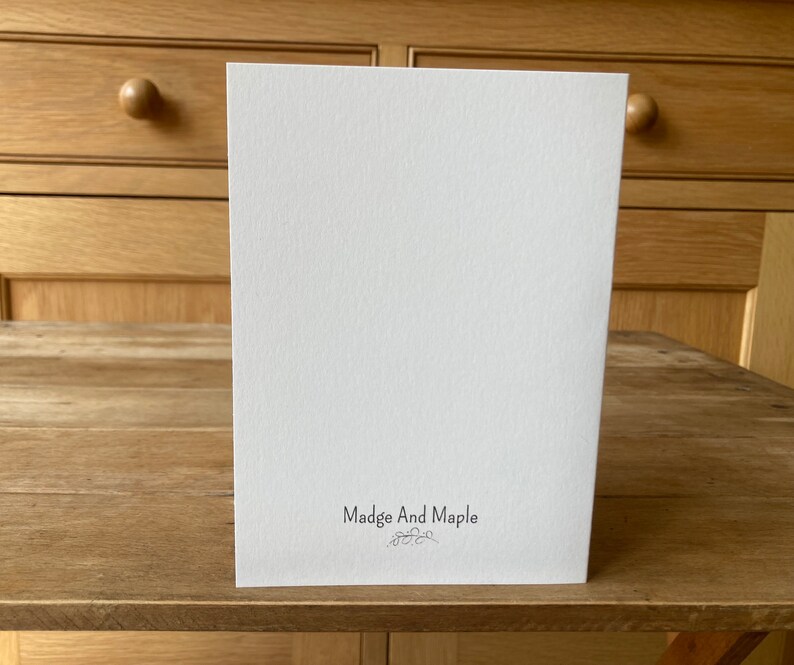 Pode incluir: Um cart&atilde;o branco em branco com o texto "Madge And Maple" impresso em preto na parte inferior.