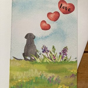 May include: A watercolor illustration of a black dog sitting in a field of purple flowers with three red hearts floating above the dog. The largest heart has the word "Love" written on it.