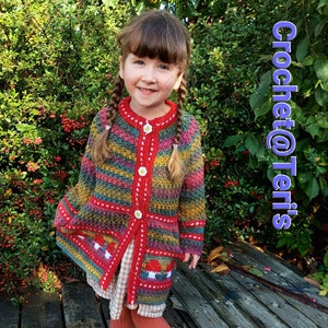 May include: A multi-colored striped crochet cardigan with a red trim and white flower buttons. The cardigan has a pocket on each side with a crocheted mushroom design. The cardigan is being worn by a child.