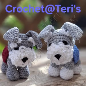 Pode incluir: Duas figuras de cão Schnauzer feitas à mão em croché com fio cinzento e branco, narizes pretos e orelhas caídas. Um cão usa um pequeno acessório vermelho nas costas e o outro um acessório azul. O texto Crochet@Teri's aparece no topo.