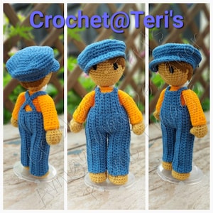 May include: A crocheted doll wearing a blue cap, orange shirt, and blue overalls. The doll is standing on a white base. The image is titled "Crochet@Teri's".