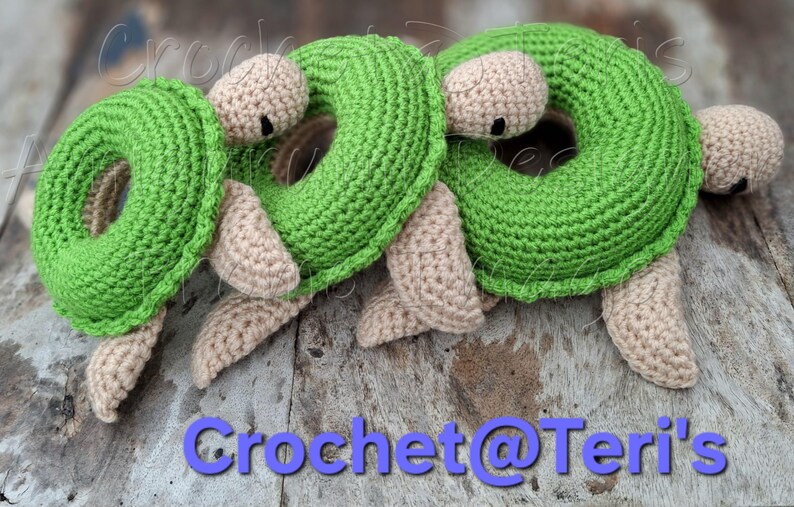 Peut inclure: Trois jouets en crochet en forme de tortue verte avec des visages et des membres beiges. Les tortues sont en forme de beigne avec un trou au centre. Les jouets sont sur une surface en bois.