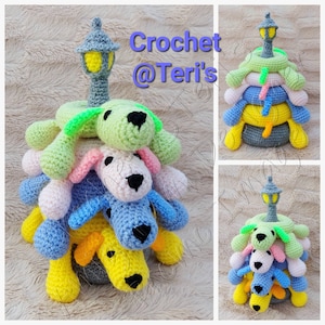 May include: A crocheted stackable toy featuring four colourful dogs with a grey lamppost on top. The dogs are green, pink, blue, and yellow. The toy is a great educational tool for children.