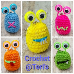 Puede incluir: Cinco llaveros de monstruo de crochet con ojos saltones. Los monstruos son azules, amarillos, rosas, naranjas y verdes. Cada monstruo tiene una expresión facial diferente.