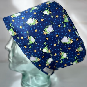 May include: A blue scrub hat with a pattern of green frogs wearing crowns and yellow stars.