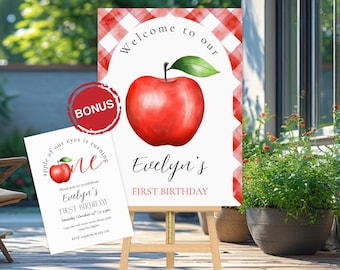 Op de afbeelding: Een welkomstbord en uitnodigingskaart voor een eerste verjaardag. Het bord toont een rode appelillustratie met de tekst "Welcome to our" en "Evelyn's First Birthday". De uitnodigingskaart heeft een appelafbeelding en de tekst "apple of our eyes is turning one."