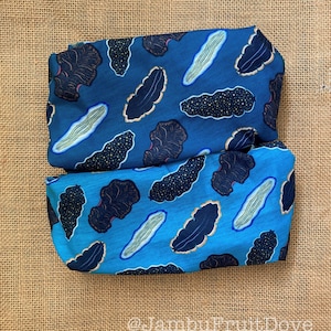 May include: Two pieces of blue fabric with a repeating pattern of dark blue sea slugs on a light blue background. The fabric is folded in half and the pattern is visible on both sides.