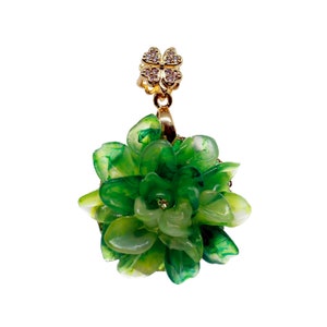 Può includere: Un ciondolo a forma di fiore di giada verde con un ciondolo a forma di quadrifoglio d'oro con strass trasparenti.