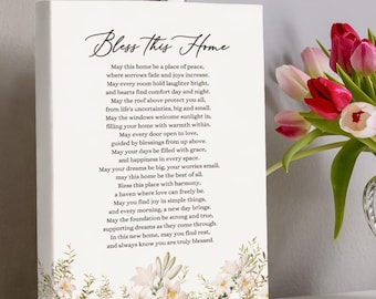 May include: A white canvas print with a floral design and a poem about home. The poem reads "Bless this Home" and includes phrases like "a place of peace", "laughter bright", and "a haven where love can freely be".