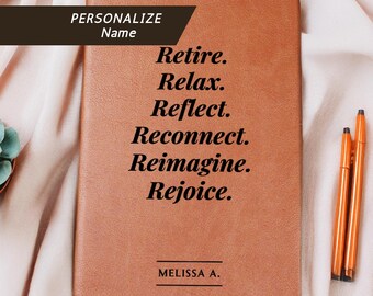 May include: A brown leather journal with the words "Retire. Relax. Reflect. Reconnect. Reimagine. Rejoice." printed on the cover. The journal has a ribbon bookmark and is next to orange pens. The text "PERSONALIZE Name" is also visible.