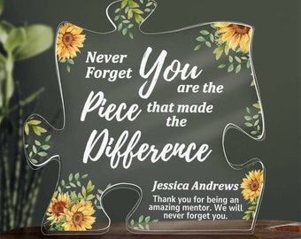 May include: A clear acrylic puzzle piece with a sunflower design and the text "Never Forget You are the Piece that made the Difference". The text "Jessica Andrews Thank you for being an amazing mentor. We will never forget you." is also included.