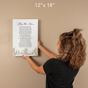 Puede incluir: Una impresi&oacute;n en lienzo de 30,5 x 45,7 cm con un dise&ntilde;o floral blanco y un poema titulado "Bless This Home". El poema expresa deseos de paz, felicidad y amor para el hogar.