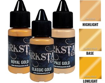 May include: Three bottles of Darkstar Miniatures paint in gold tones: Royal Gold, Classic Gold, and Pale Gold. Each bottle has a black cap and a label with the brand name and website. Color swatches for highlight, base, and lowlight are also shown.