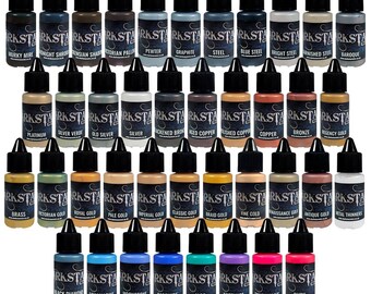 May include: Collection of small paint bottles with black caps, labeled with various metallic and gemstone colors like "Graphite," "Ruby," and "Brass." The bottles are arranged in neat rows, showcasing a wide range of shades for artistic projects.