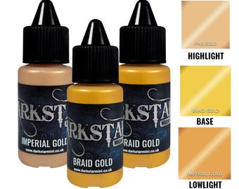 May include: Three small bottles of metallic paint with black caps. The bottles are labeled "Imperial Gold", "Braid Gold", and "Raid Gold". Color swatches show "Fine Gold", "Braid Gold", and "Imperial Gold". The text "Darkstar Miniatures" is visible on the bottles.