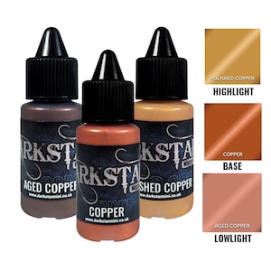 Puede incluir: Tres botes de pintura acrílica metálica en tonos cobre. Los botes están etiquetados como "Aged Copper", "Copper" y "Polished Copper". Las muestras de color muestran los tonos "Highlight", "Base" y "Lowlight". El texto "Darkstar Mini" y una dirección web son visibles.
