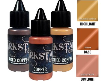 May include: Three bottles of metallic acrylic paint in copper tones. The bottles are labeled "Aged Copper", "Copper", and "Polished Copper". Color swatches show "Highlight", "Base", and "Lowlight" shades. The text "Darkstar Mini" and a website address are visible.