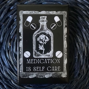 May include: Black and white illustration of a bottle with a flower inside and pills around it. The text "MEDICATION IS SELF CARE" is below the bottle.