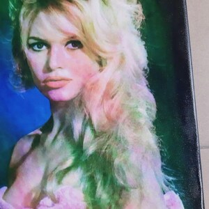 Może przedstawiać: Wydruk na pł&oacute;tnie przedstawiający portret kobiety z blond włosami i r&oacute;żową szatą. Obraz ma estetykę vintage z miękką paletą kolor&oacute;w r&oacute;żu, zieleni i błękitu. Podpis artysty jest widoczny w lewym dolnym rogu.