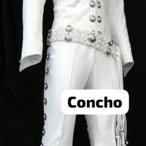 May include: White jumpsuit with silver-tone button details and a matching belt. The outfit features a red inner lining at the collar and the word "Concho" is visible on the pants. The pants have silver-tone buttons down the side.