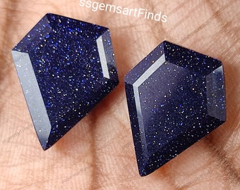 May include: Two blue star sapphire gemstones cut in a kite shape. The gemstones are faceted and have a sparkly, glittery appearance.