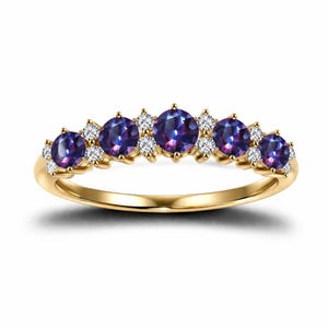 Puede incluir: Un anillo de oro con cinco piedras preciosas redondas de color púrpura oscuro y pequeñas piedras blancas. La banda del anillo es dorada y las piedras están dispuestas en una fila. Una joya.