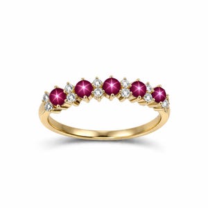 Könnte beinhalten: Ein goldener Ring mit einer Reihe von tiefroten Edelsteinen und kleinen weißen Diamanten. Die Edelsteine sind gleichmäßig über die Oberseite des Rings verteilt.