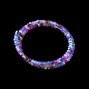 May include: A multi-coloured beaded bracelet with shades of pink, blue, and purple. The beads are iridescent and have a sparkly finish.