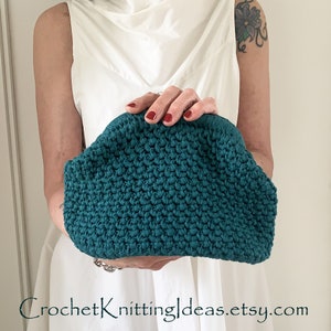 Puede incluir: Un bolso de mano de crochet de color turquesa. El bolso está hecho con un punto texturizado y tiene una forma redondeada.